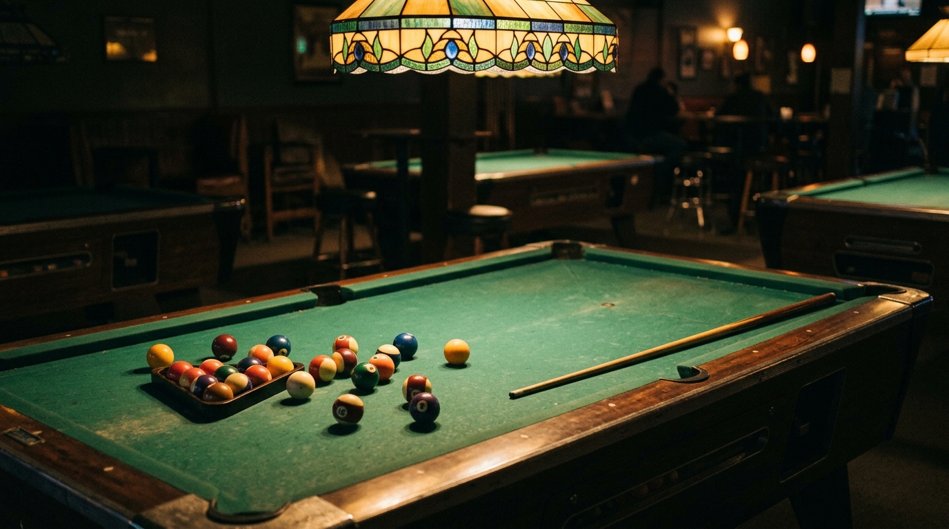 Empty pool table under a tiffany lamp, quiet pool hall at night